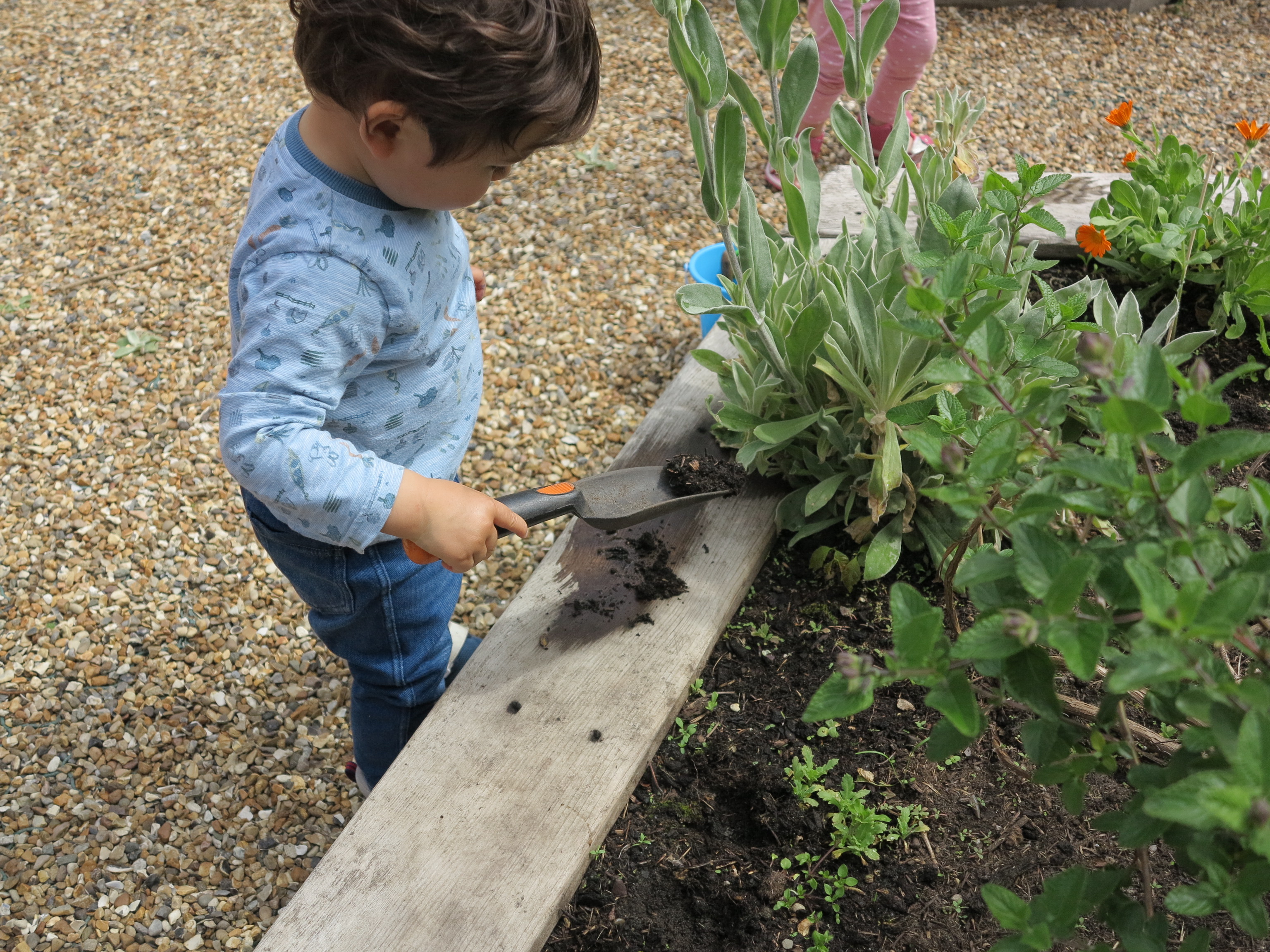 A photograph of a child digging into a flower bed.